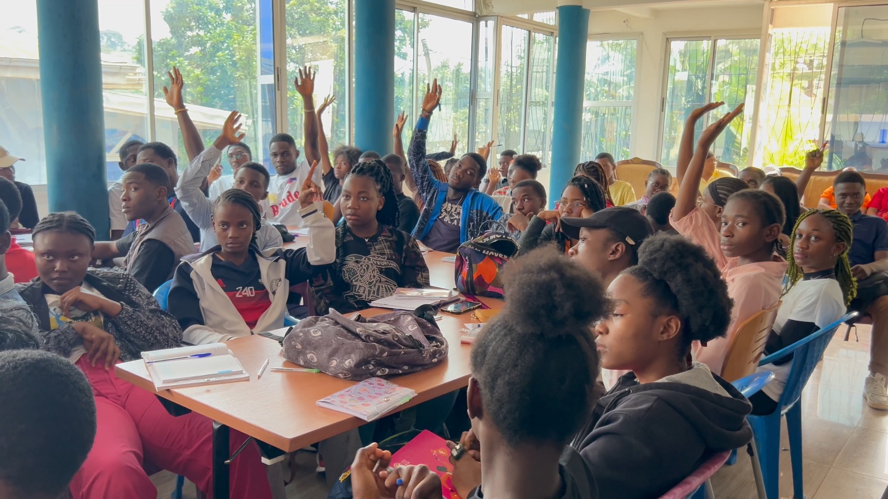 Students raising their hands during a PICHNET youth capacity session in Yaoundé.